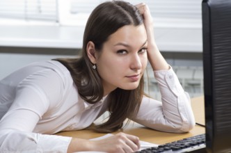 Attractive young caucasian brunette businesswoman sitting in her office