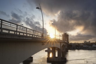 A road or motorway leads through an old historic city gate. Sunset in the evening over the Rhine