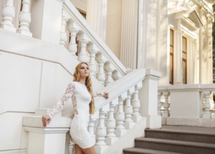 Beautiful blond woman in white dress outdoors on the stairs