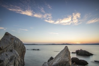 View through rocks on a sandy beach into the sunset. Landscape shot with view to the horizon over