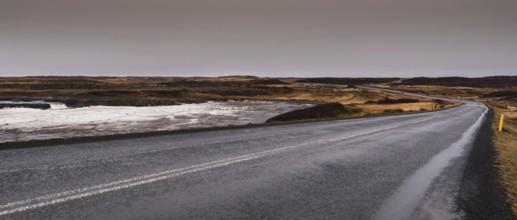 Empty asphalt motorway main road with icy frozen lake in Iceland