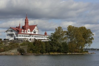 This image captures a historic seaside building with distinctive red roofs, nestled on a small