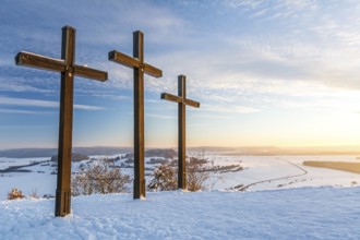 Summit crosses on a mountain peak in a beautiful winter landscape in the Swabian Alps at sunset