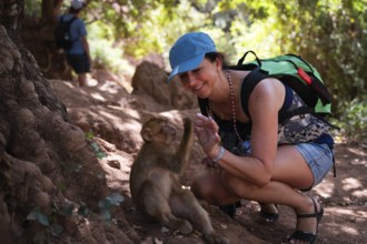 The tourist is having fun with macaque monkey near the Ouzoud waterfall, Morocco, Africa