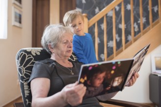 Grandmother and grandson watching photo album with the grandson pictures on the cover