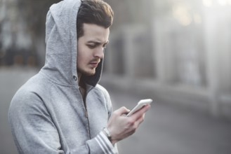 Happy teen boy walking on the street and using a smart phone