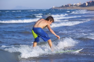 Boy surfer surfing waves on the beach enjoying fun