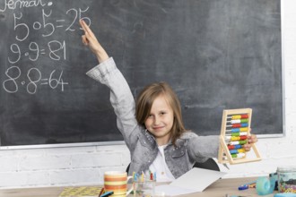 The girl raised her hand in class. The student knows the solution of the task given by the teacher.