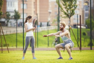 Team work in sports. female trainer training man with beard in park on green grass, lawn at sunset.