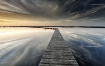 Wooden path on water on big lake before sunset