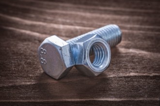 Threaded metal bolt and screw nut on vintage wooden board repairing concept