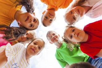 Cute girls and boys in colorful clothes standing together in circle looking at the camera on the