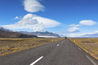 Highway through South Icelandic landscape under a blue summer sky with clouds