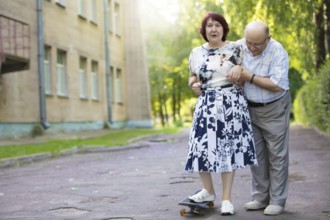 Happy elderly couple with a skateboard. Handsome man and woman seniors. Husband and woman in old