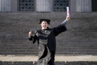 Woman recently graduated, dressed in cap and gown, with her degree in her hand, celebrating