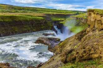Tundra on a sunny summer day. The waterfall in Iceland - Gullfoss on the Hvitau River. Huge masses