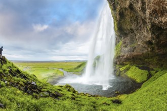 Seljalandsfoss waterfall in July. Passage under the waterfall. Photo taken fisheye lens. Warm
