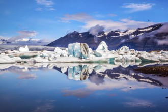 Icebergs and ice floes are reflected in the smooth water surface. Drift ice Ice Lagoon -