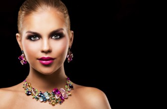 Beautiful woman with dark makeup and pink lipstick posing on black background wearing flower spring
