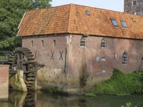Detailed view of a brick watermill with water wheel and surrounding vegetation, winterswijk,