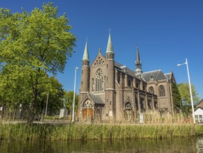 Impressive church with towers and grand architecture, surrounded by trees under a blue sky,