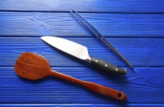 Chef tools knife tweezers and spatula on a blue wooden background