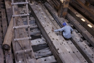 Shipbuilder working on a wooden boat under construction, Mandvi, Gujarat, India, Asia