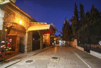 Street in Muslim Quarter in Jerusalem old city and stall .People in distance. Blue hour, twilight