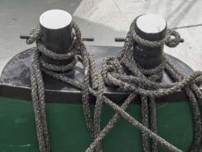 Close-up of two black metal bollards on a boat, surrounded by ropes and knots, carolinensiel,