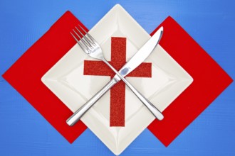 White square plate and red Christmas decoration on the blue wooden table.Top view.Flat Lay Image