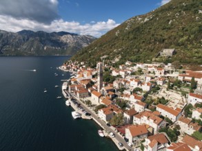 Cars parked on the promenade near the bell tower of the Church of St. Nicholas. Perast, Montenegro.