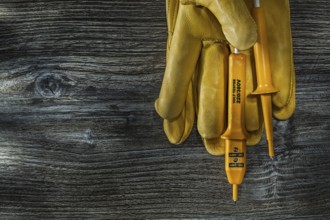 Electric tester leather safety gloves on vintage wooden board