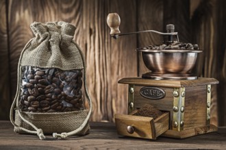 Vintage sack with coffee beans and wooden mill on wood background