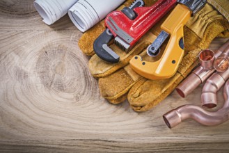 Construction drawings protective gloves monkey wrench pipe cutter fixtures on wooden board plumbing
