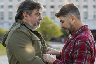 A man is adjusting his husband's jacket