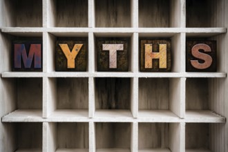 The word MYTHS written in vintage ink stained wooden letterpress type in a partitioned printer's
