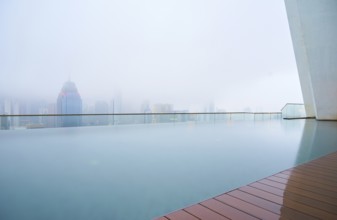 Swimming pool on roof top with beautiful city skyline view, early morning with mist, kuala lumpur