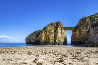 Yellow rocks and cliffs on a sandy beach. A bay by the sea, over which the old stone bridge of the