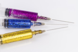 Close up of syringes with colorful glitter. Isolated on white