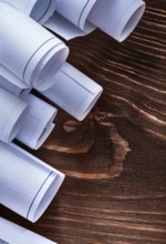 Rolls of construction plans on vintage wooden pine board maintenance concept