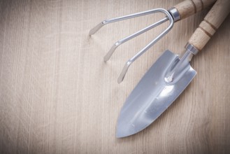 Stainless gardening trowel fork with sharp hand spade on wooden board horizontal version