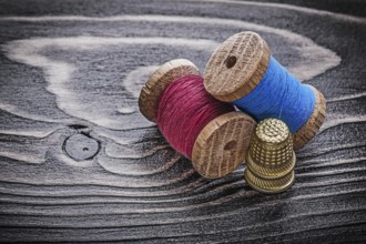 Vintage spools of thread thimbles on wooden board fancy-work concept
