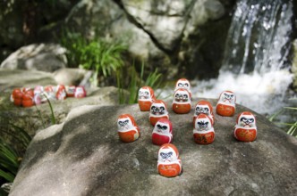 Traditional japanese Daruma dolls in front of a water fall at Katsuo Ji Temple in Mino, Japan,