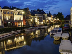 Evening view of the river with illuminated historical buildings and boats, Ghent, Belgium, Europe