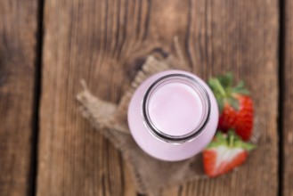 Milk (Strawberry flavoured) on wooden background (selective focus)