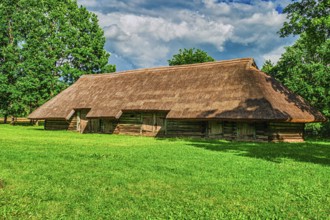 Old Wooden Barn with Green Grass and Blue Sky Background