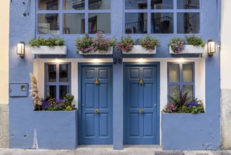 Detail of a building with a blue façade and two symmetrically arranged doors and windows, richly