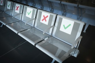 Empty chairs on an airport terminal with signs to keep social distance for the preventions of