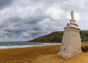 Ramla Bay, Malta, 20 December, 2023: view of the red sand beach and Staue of Our Lady in Ramla Bay
