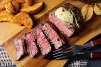 Rustic medium rare beef steak with herbs and potato wedges
